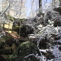 Snow on the rocks by the waterfall.